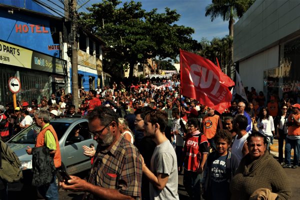 Rua tomada por muitos manifestantes na rua, segurando bandeiras e protestando durante a greve