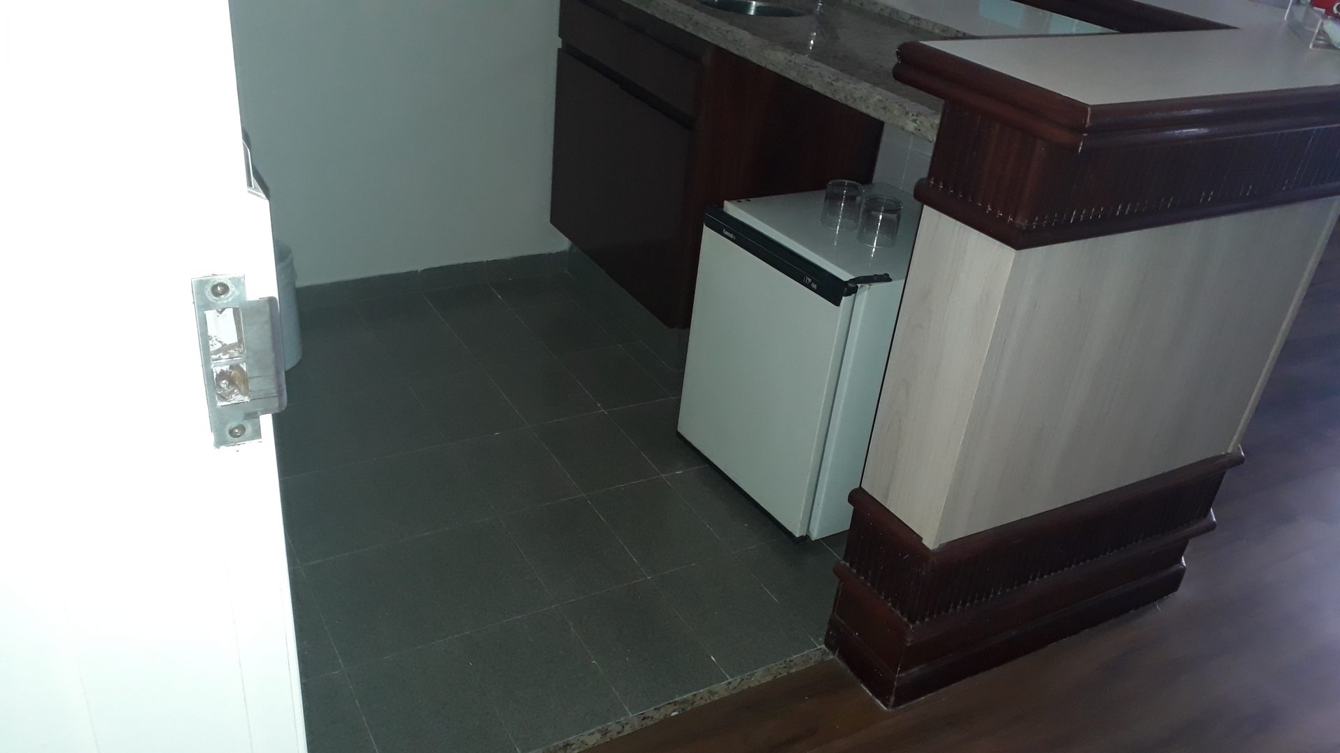 Imagem de um vão de acesso de uma cozinha em um quarto adaptado de hotel em Bauru. A imagem mostra um vão largo, com uma pia e um frigobar acoplado no móvel. Acessibilidade